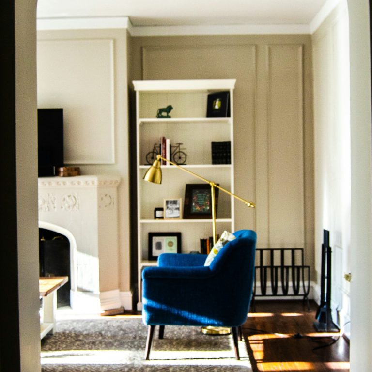 Blue armchair beside a bookshelf in a bright, minimalist living room.