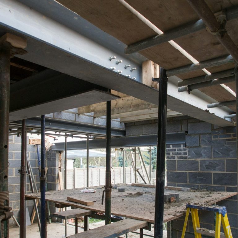 Interior view of a construction site with scaffolding and a wooden workbench.